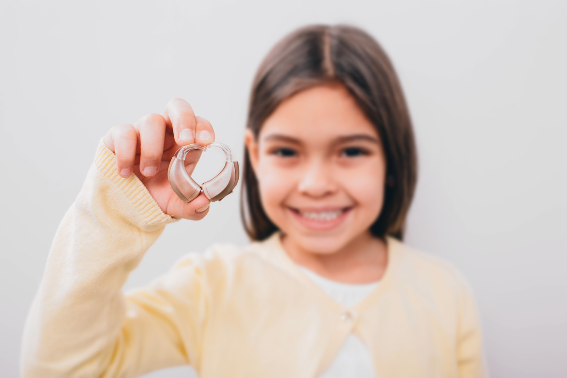 advertising hearing aid for children, a mixed race child shows a hearing aid. Children's hearing treatment